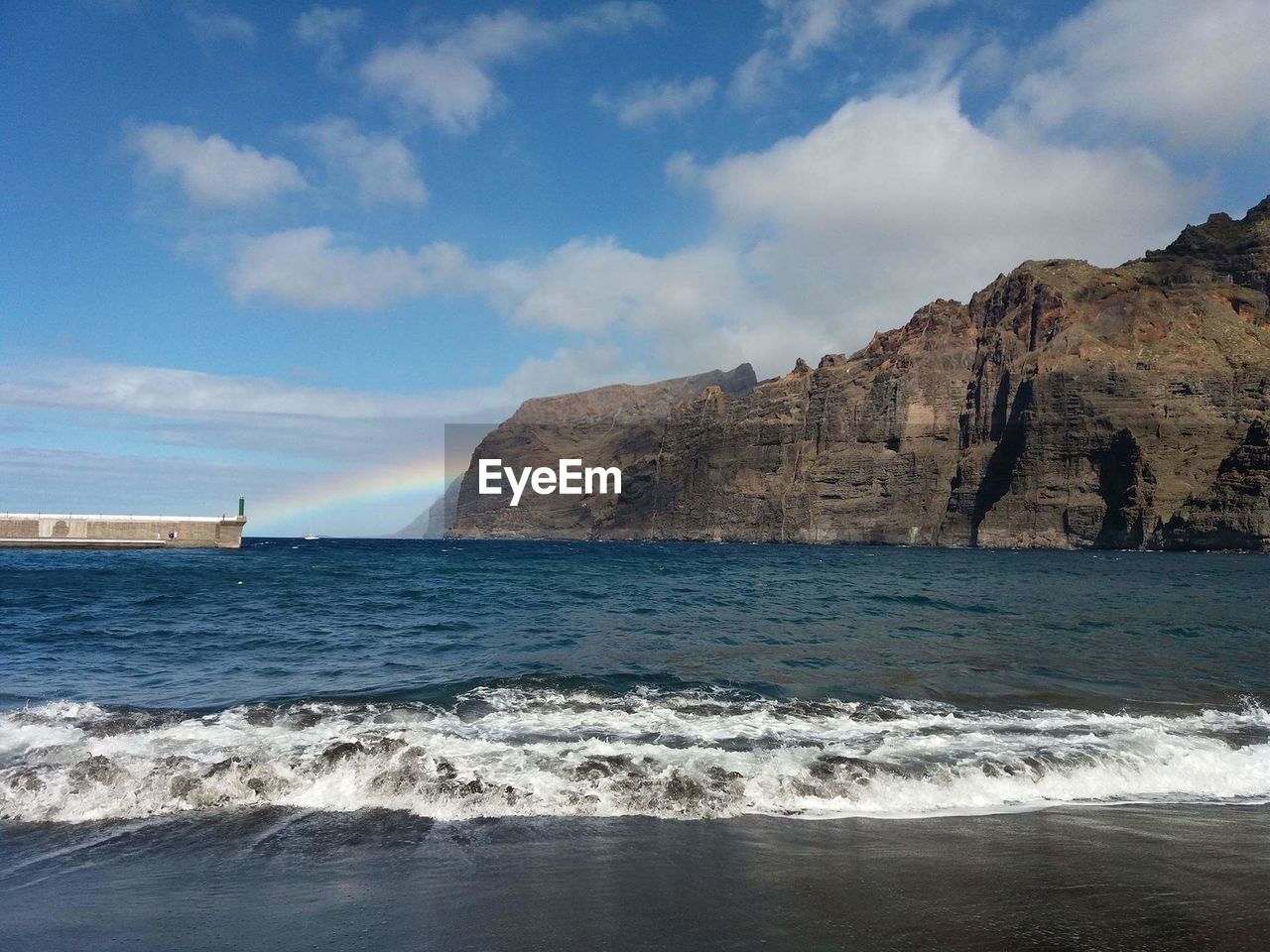 Scenic view of sea and mountain against sky