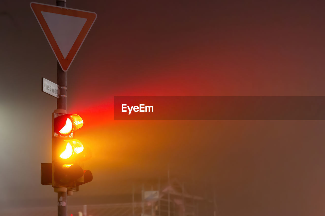 Low angle view of traffic light in foggy night