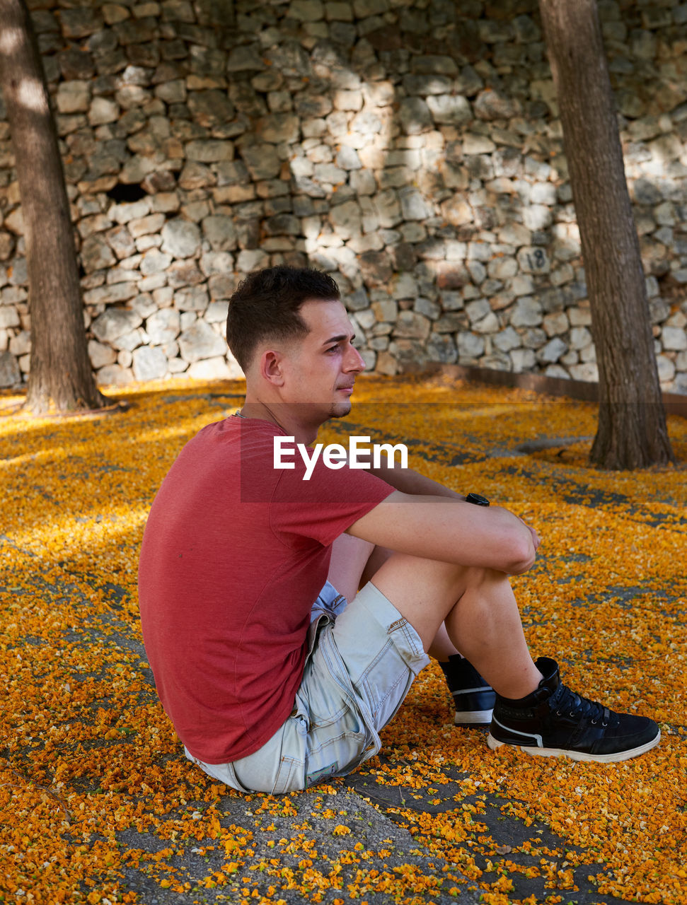 A young attractive boy in a red t-shirt posing in a park.