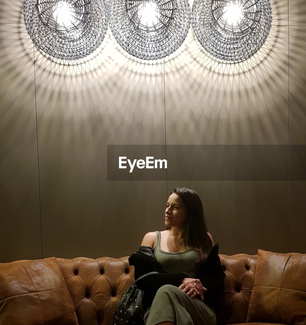 Woman sitting on sofa in illuminated room