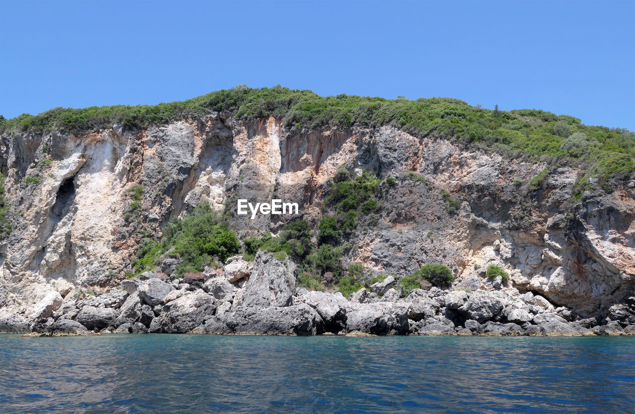 Rock formations by sea against clear sky