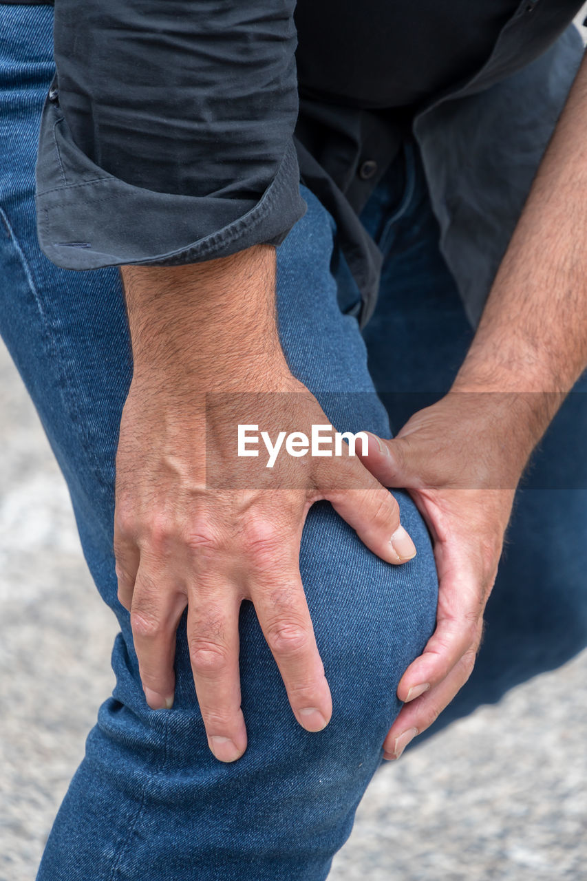 MIDSECTION OF MAN WITH HANDS STANDING ON GROUND