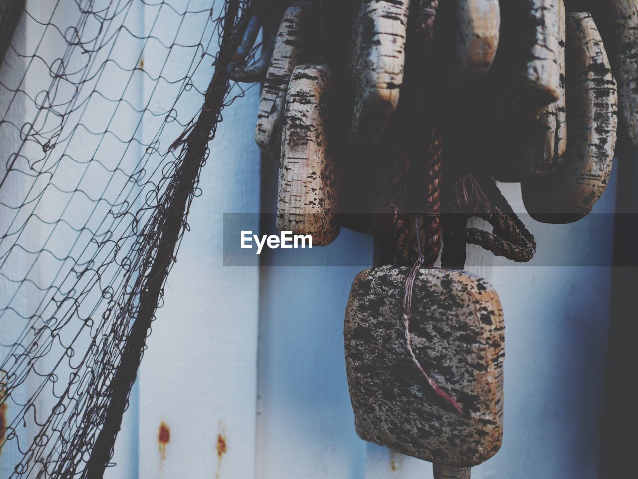 Close-up of fishing net with buoys by wall