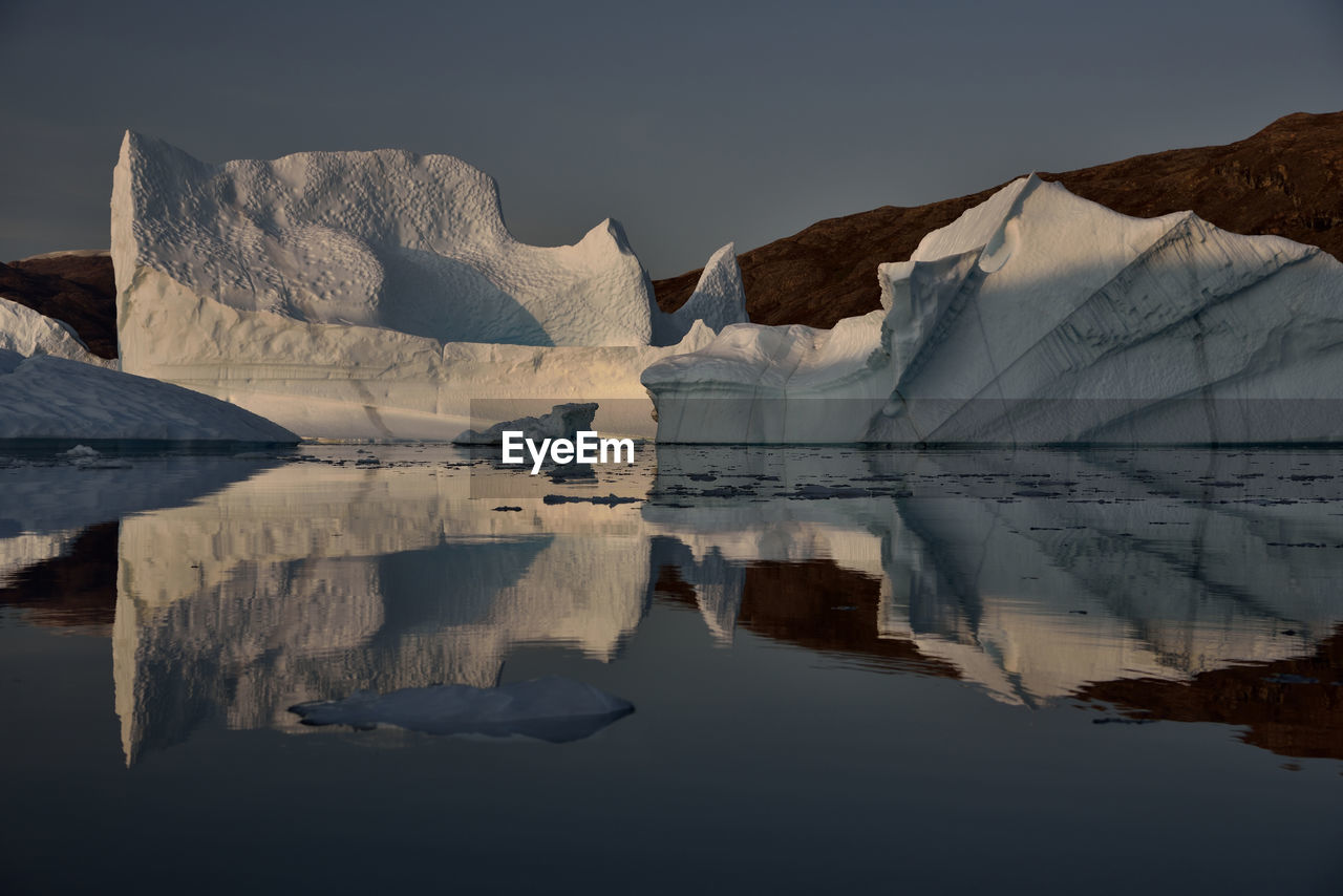 Scenic view of iceberg shapes and reflectins in mirror-like sea in greenland scoresby sound