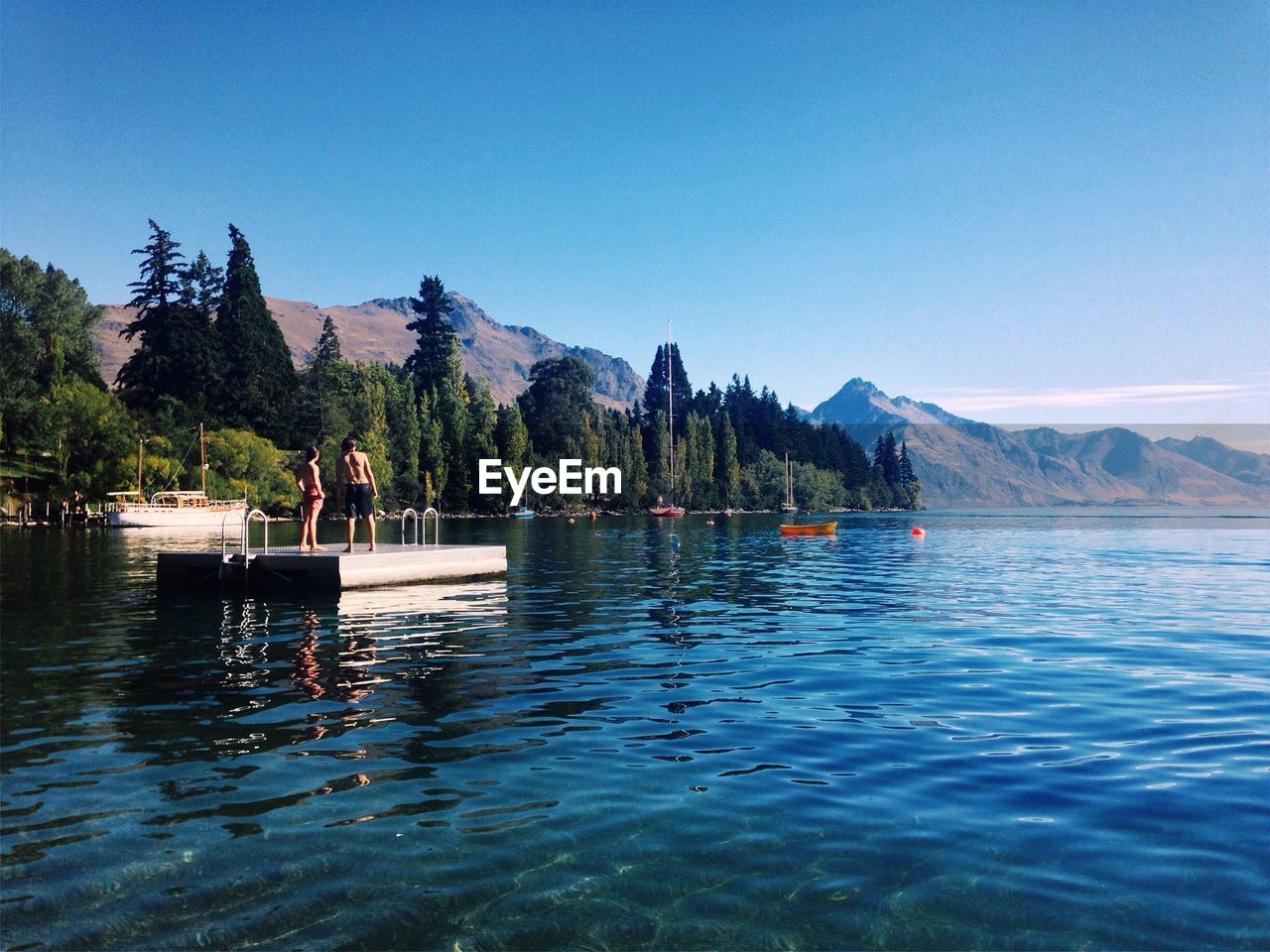 People standing on floating platform in lake