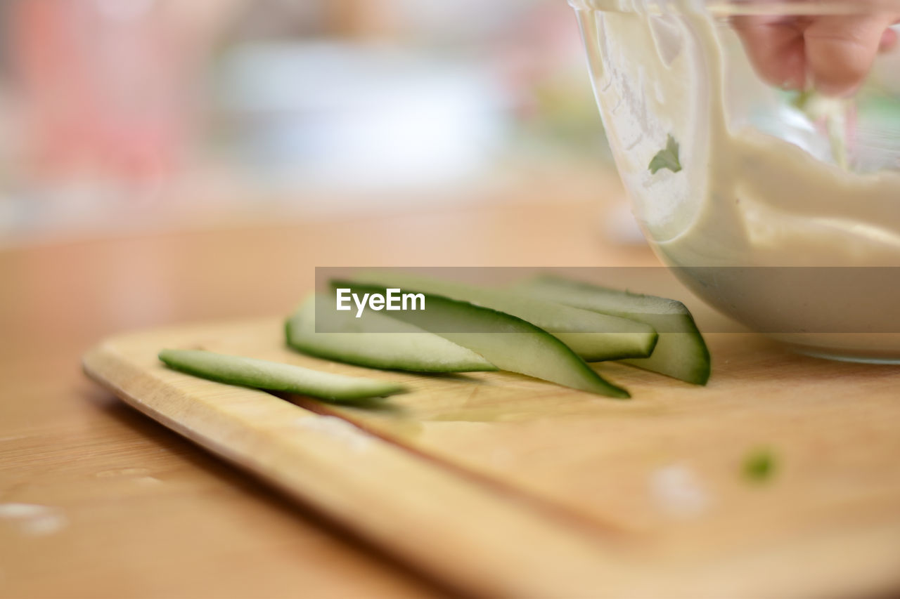 CLOSE-UP OF HAND HOLDING BREAD ON CUTTING BOARD