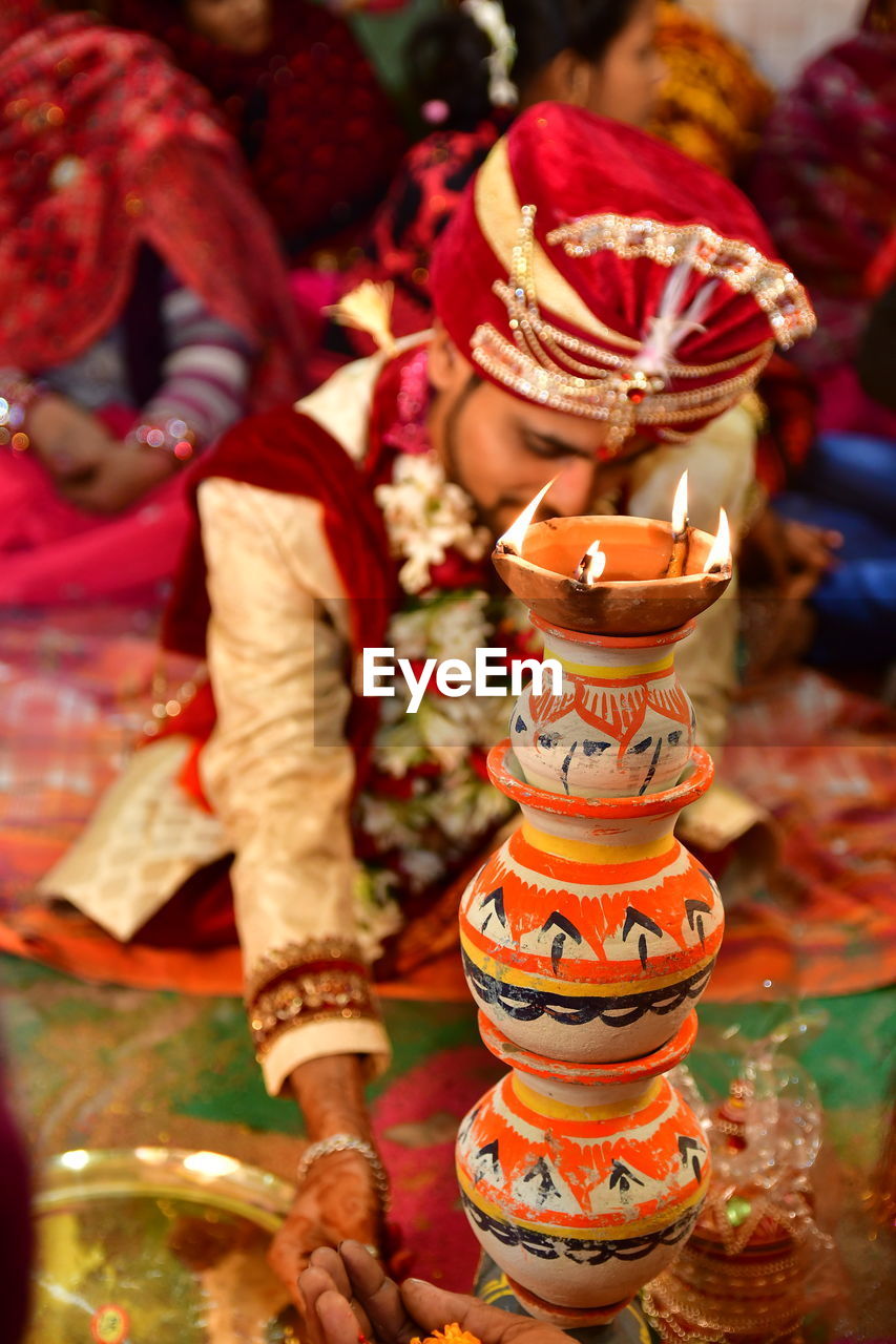 Bridegroom sitting by diya during wedding ceremony