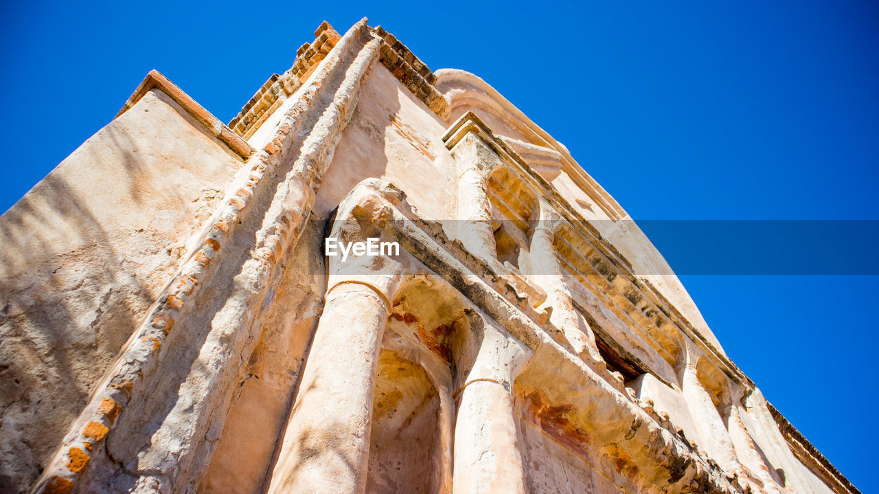 Low angle view of old ruin against clear blue sky during sunny day