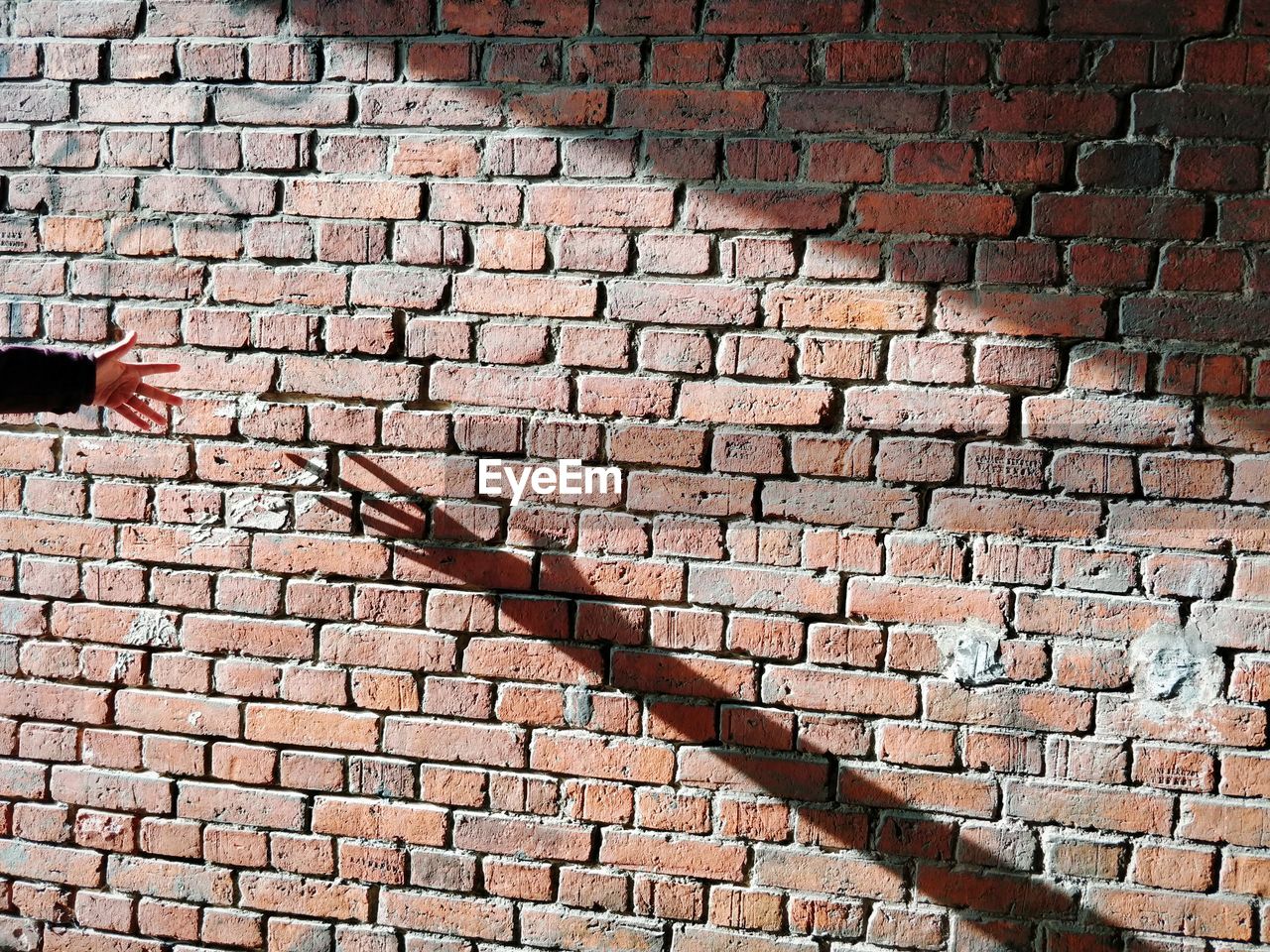 Full frame shot of brick wall with shadow of a human hand