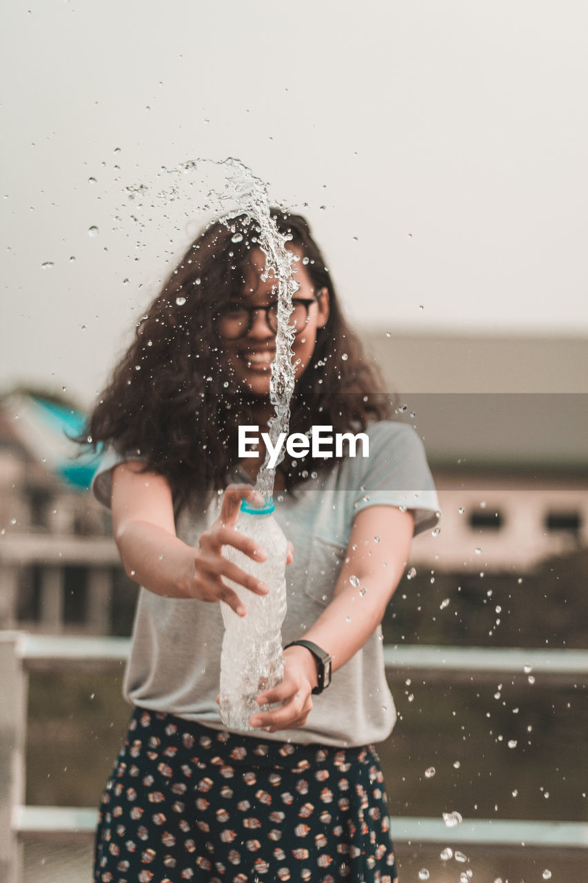 Young woman splashing water from bottle
