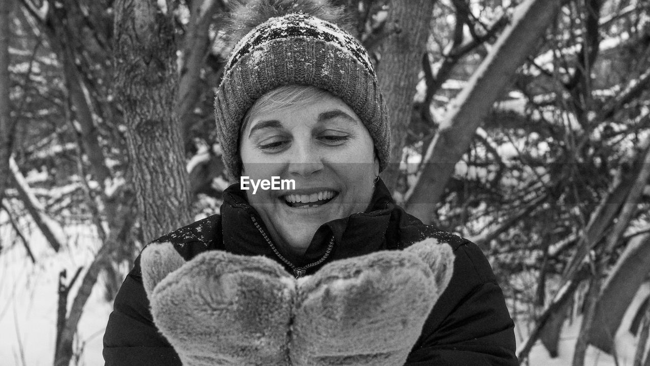 PORTRAIT OF SMILING YOUNG WOMAN IN SNOW