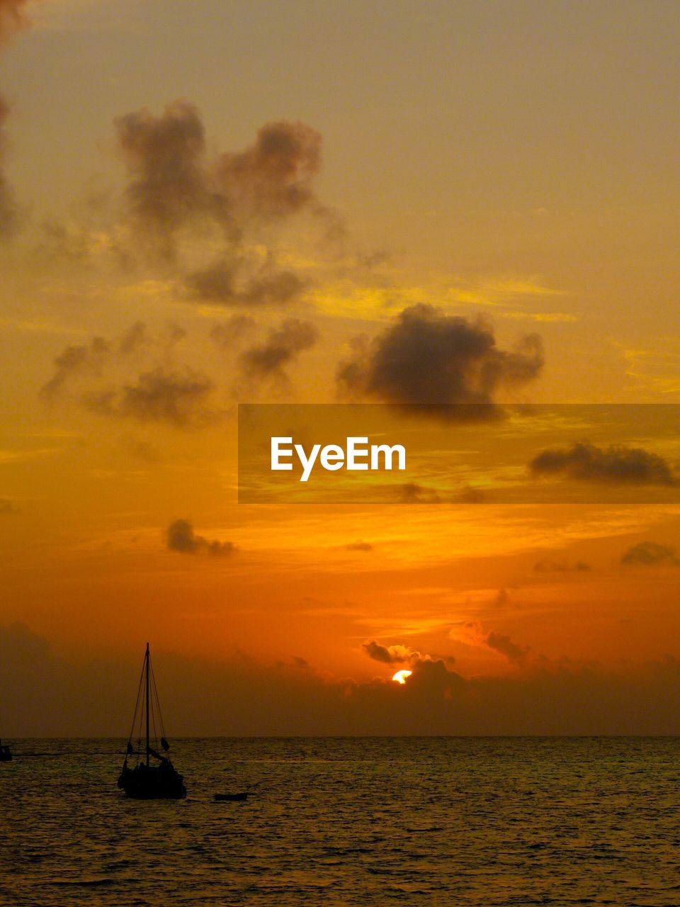 Silhouette of sailboat in sea during sunset