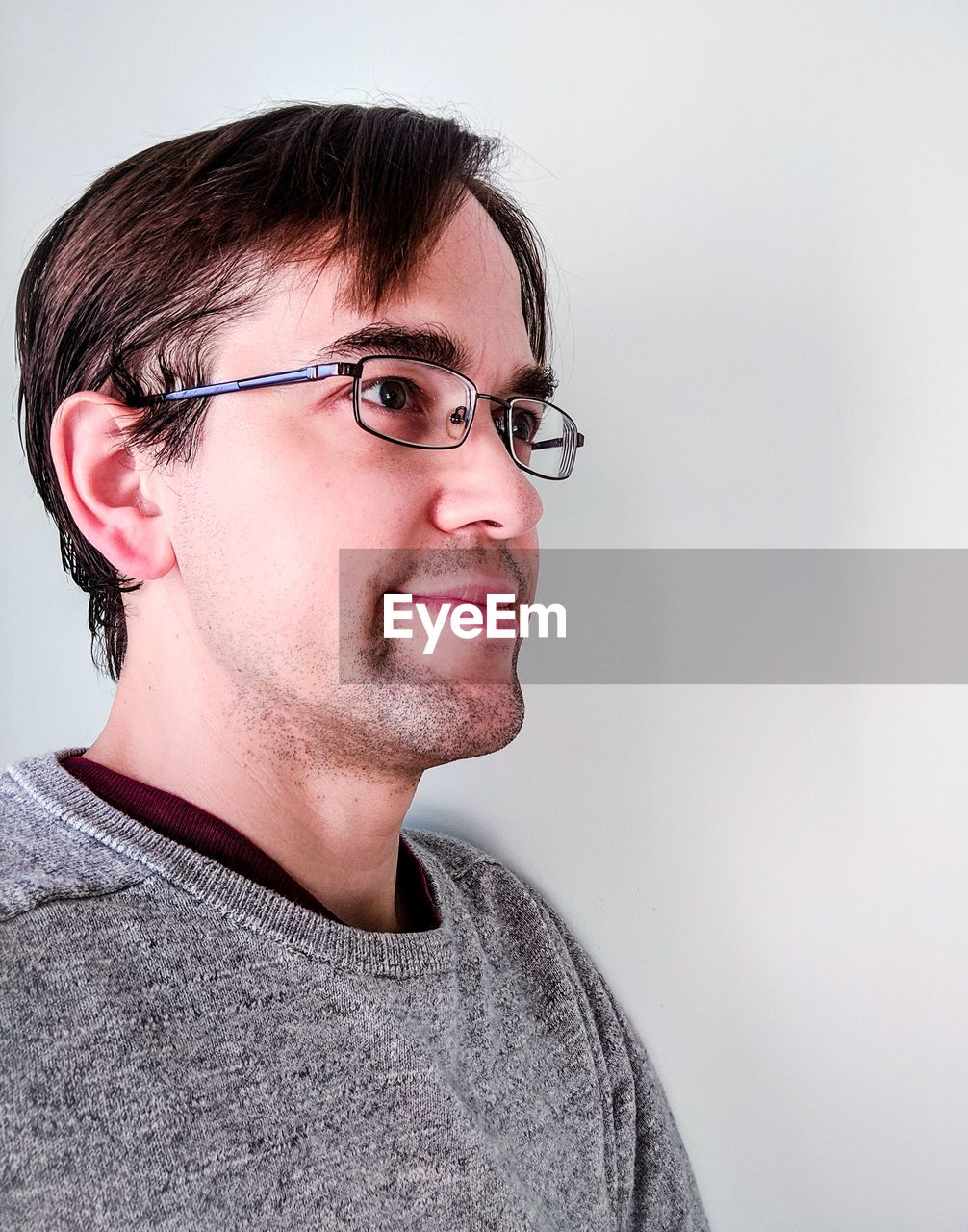 Man in eyeglasses looking away against white background