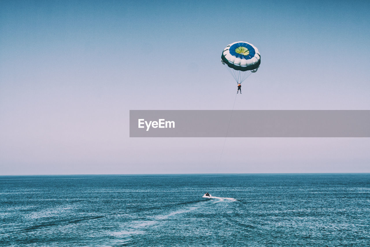 Person parasailing over sea against sky