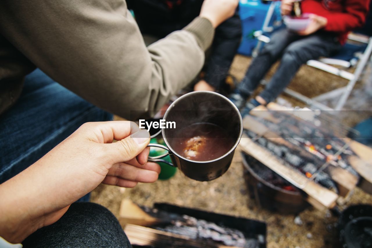 Cropped hand holding coffee at campsite