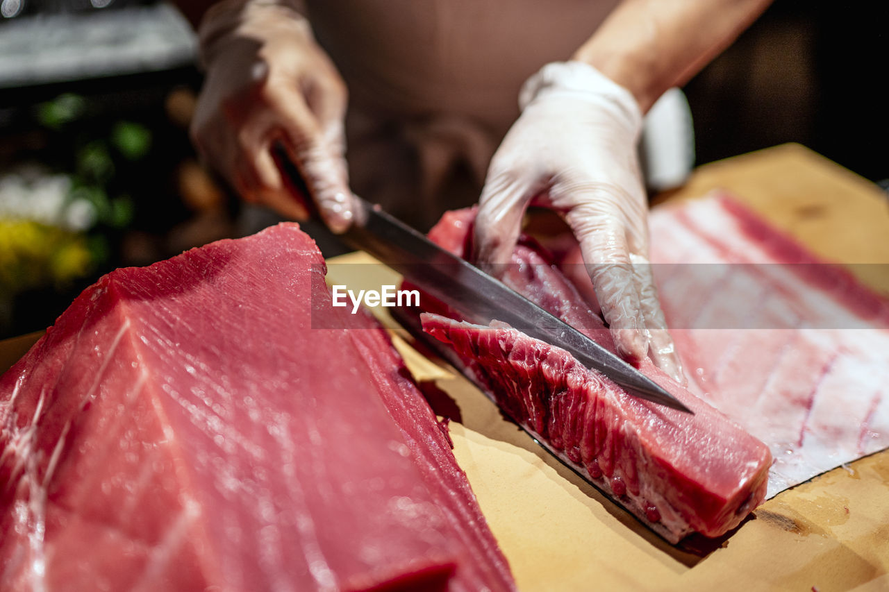 Male chef cutting raw seafood into slices at restaurant