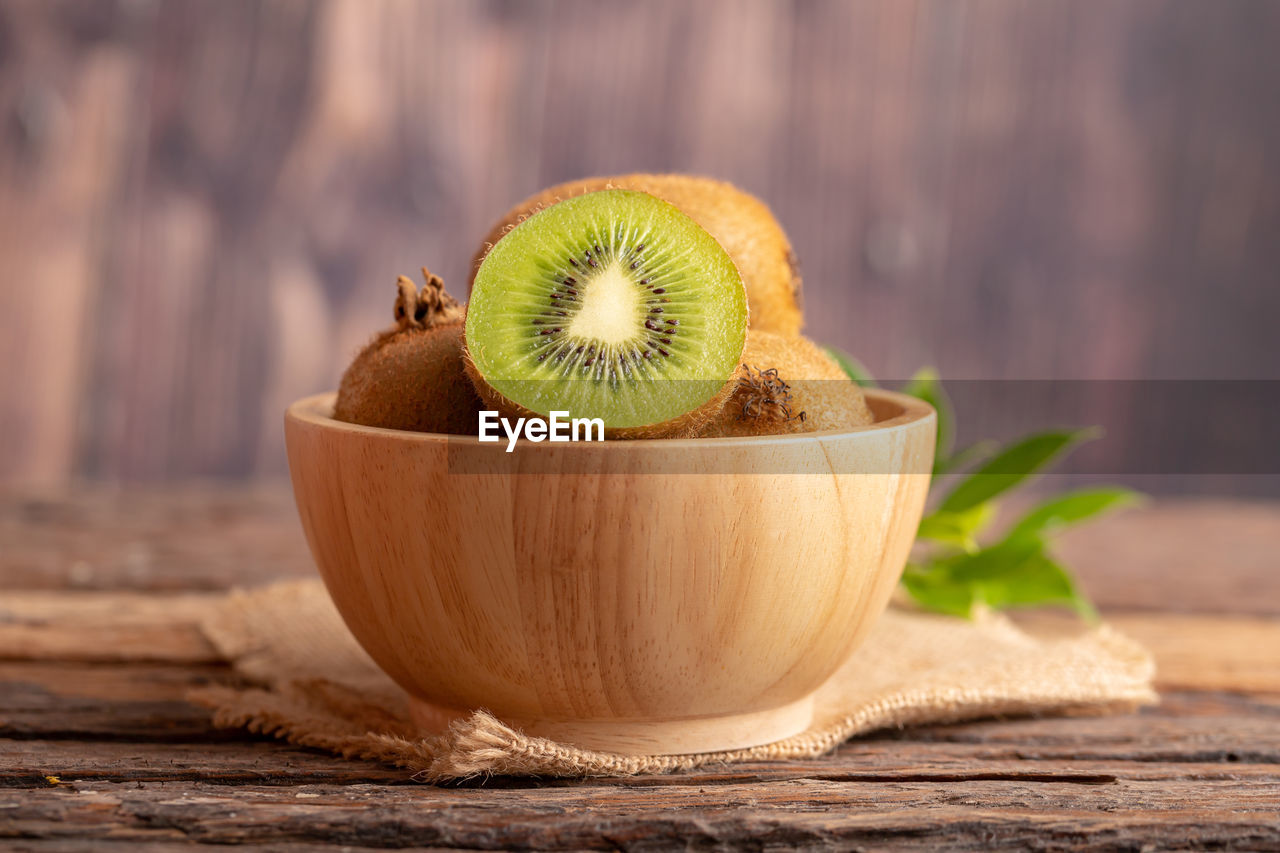 A half of fresh green kiwi in a wood bowl