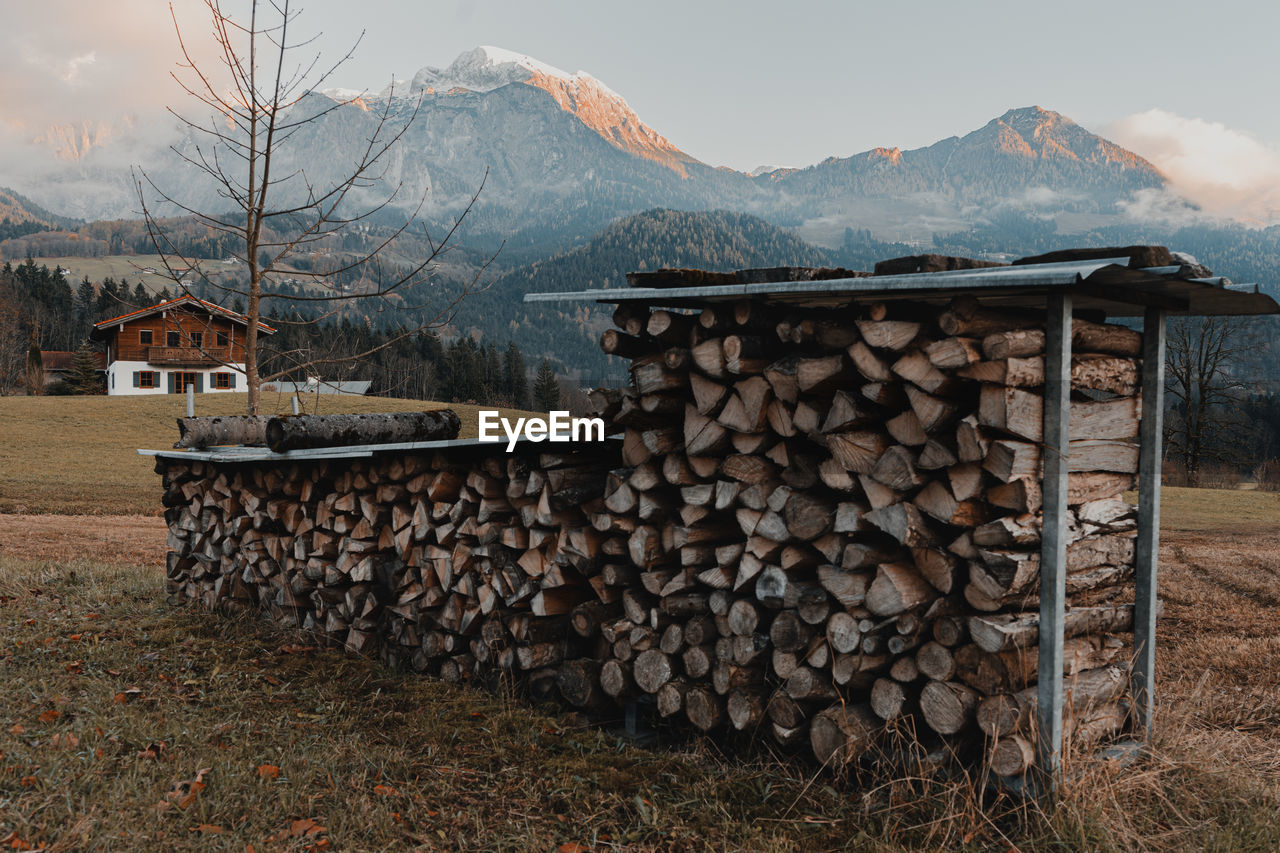 STACK OF LOGS IN MOUNTAINS AGAINST SKY