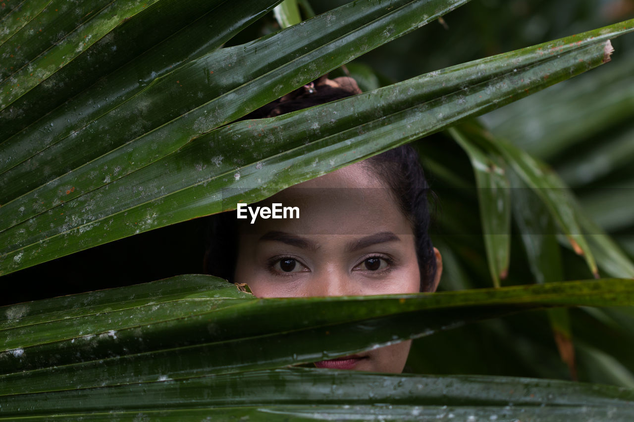 Close-up portrait of mature woman standing by plants