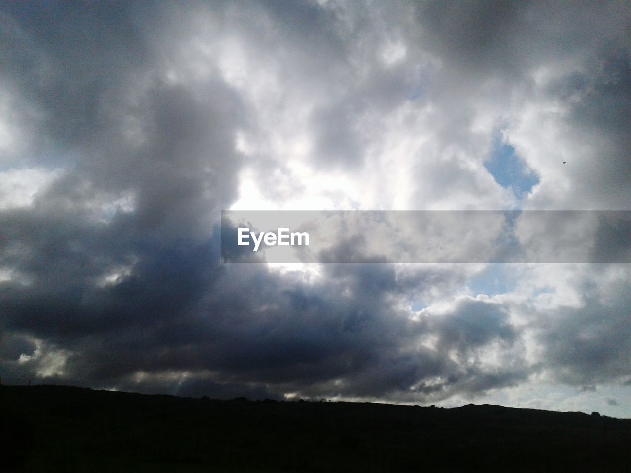 STORM CLOUDS OVER SILHOUETTE LANDSCAPE