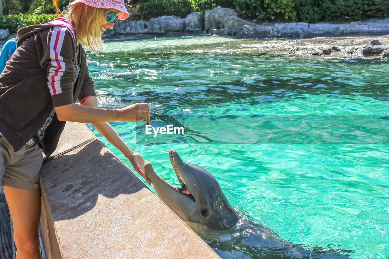 Woman touching fish in water