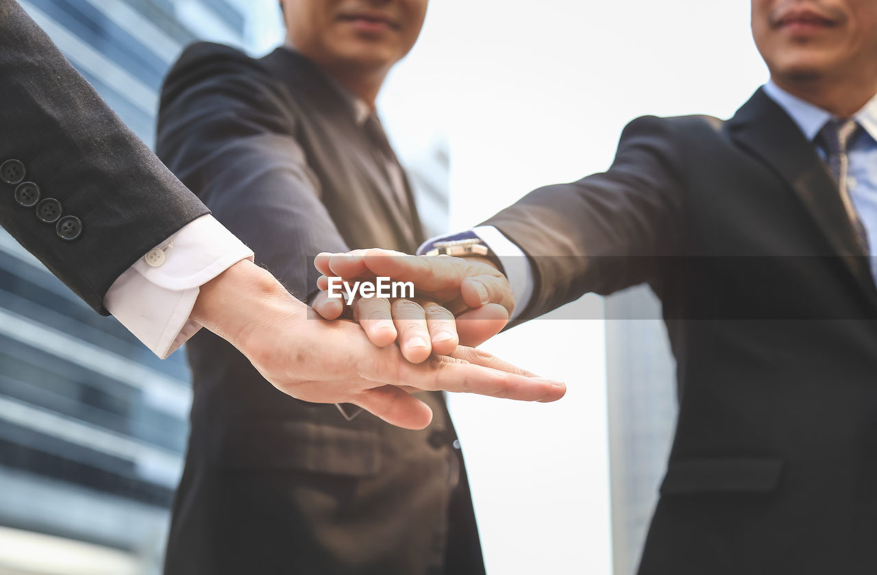 Businessmen with stacked hands in city