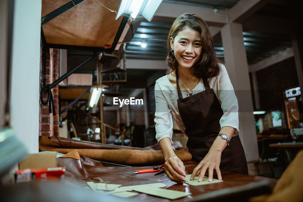 portrait of smiling young woman using mobile phone in office