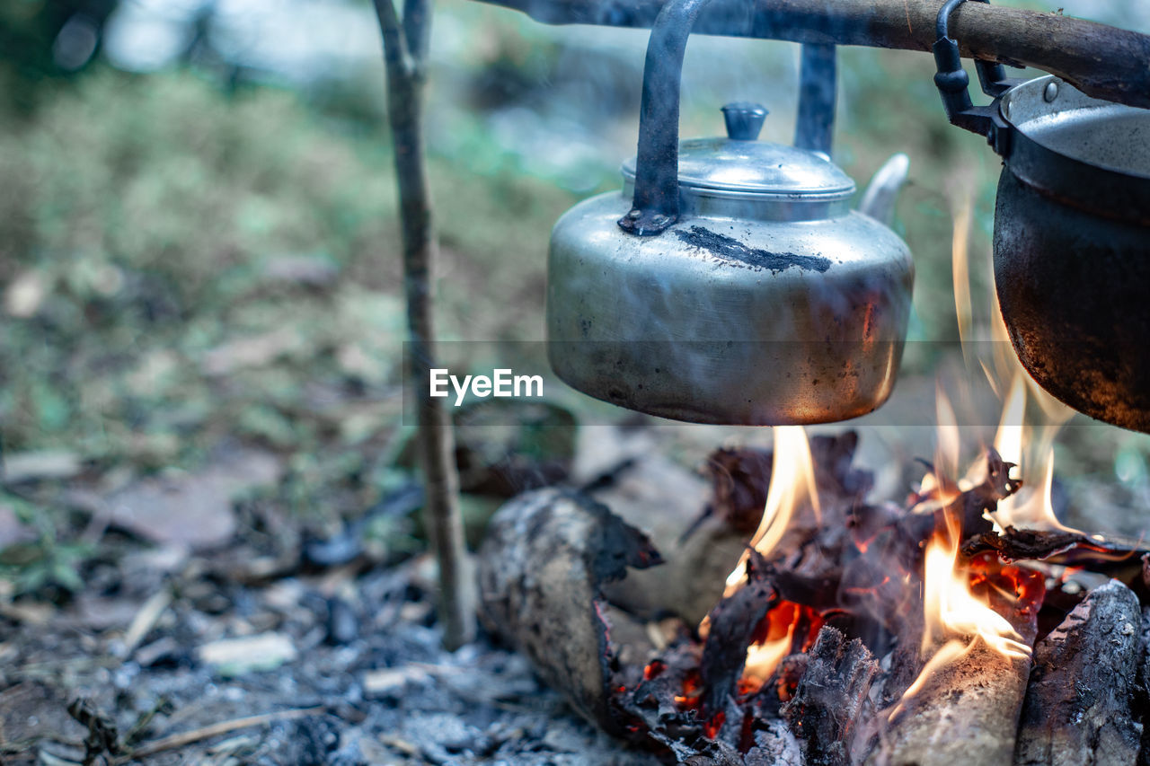 CLOSE-UP OF BURNING CANDLES ON WOODEN LOG