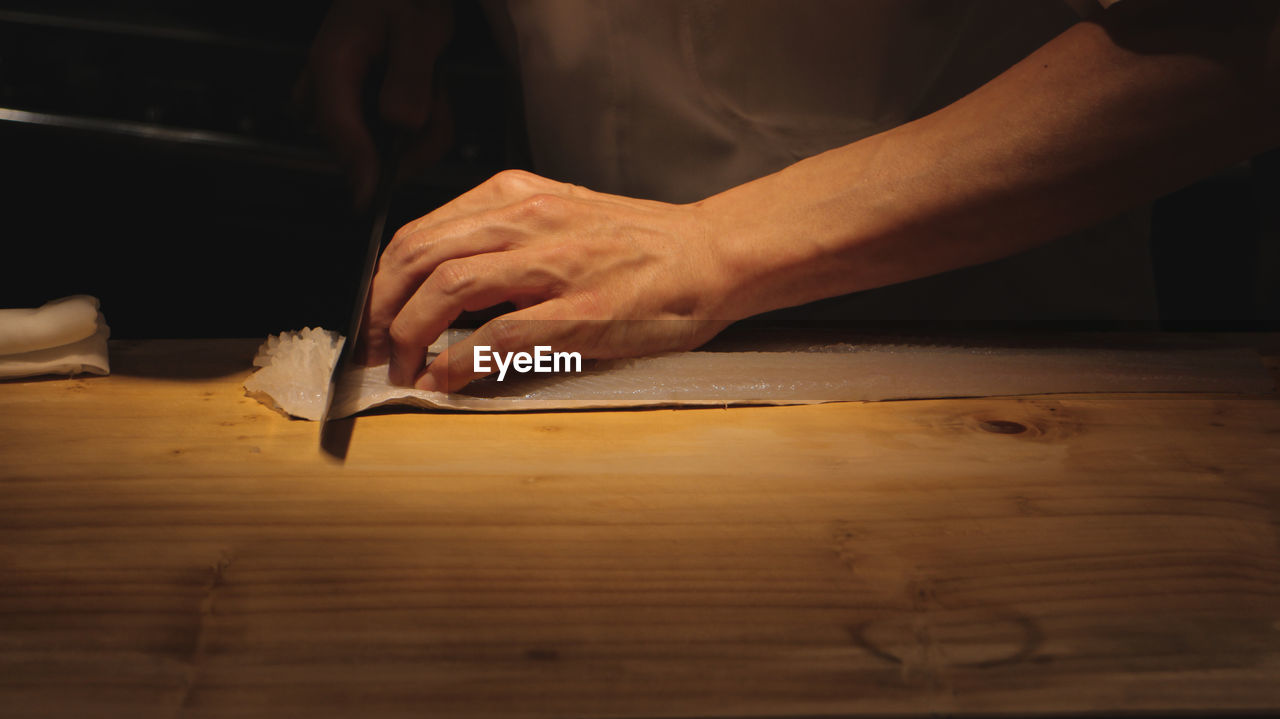 Midsection of man cutting fish at table