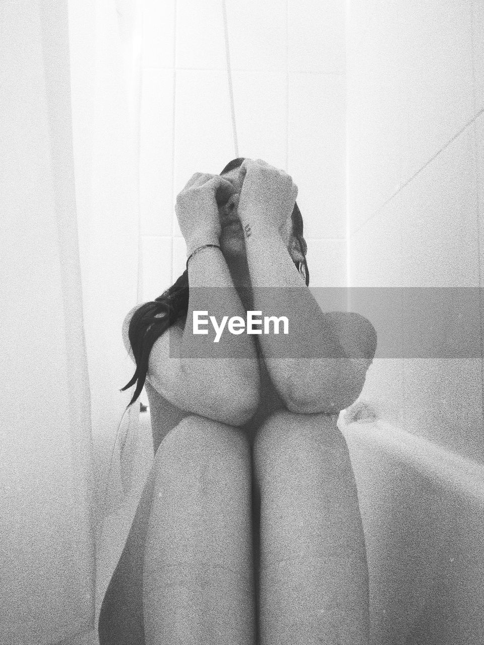 Naked woman sitting in bathtub at home
