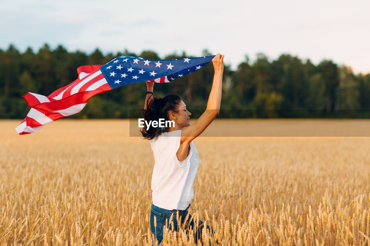 REAR VIEW OF WOMAN STANDING IN FIELD