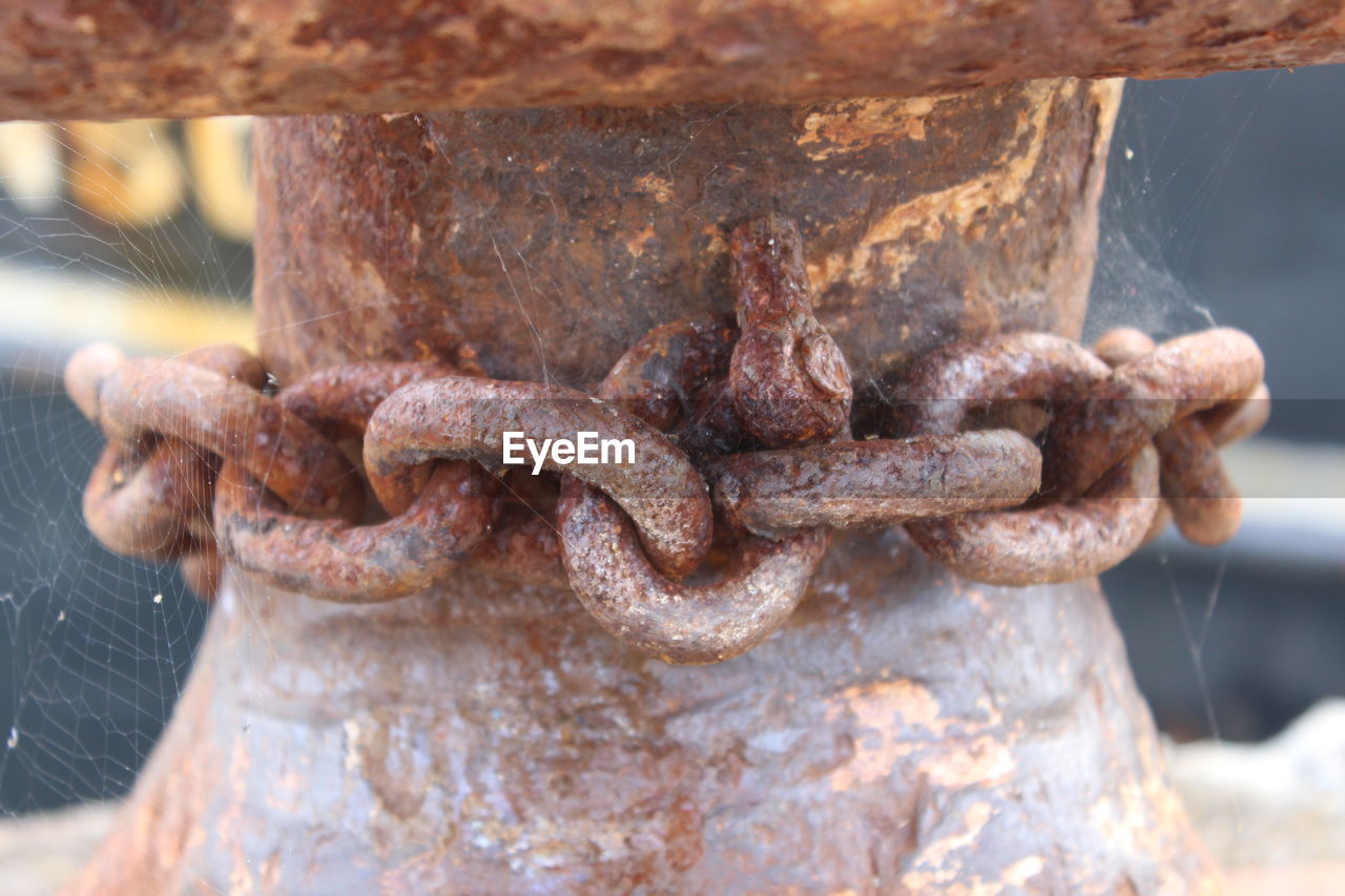CLOSE-UP OF RUSTY CHAIN ON METAL