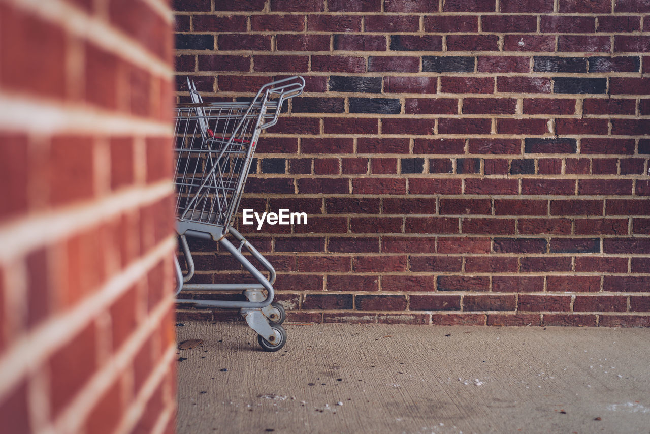 View of shopping cart against brick wall