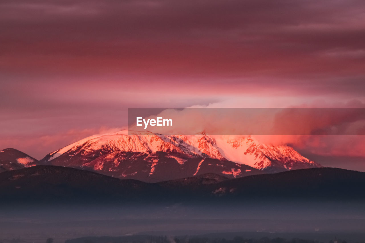 SCENIC VIEW OF SNOWCAPPED MOUNTAIN AGAINST ORANGE SKY