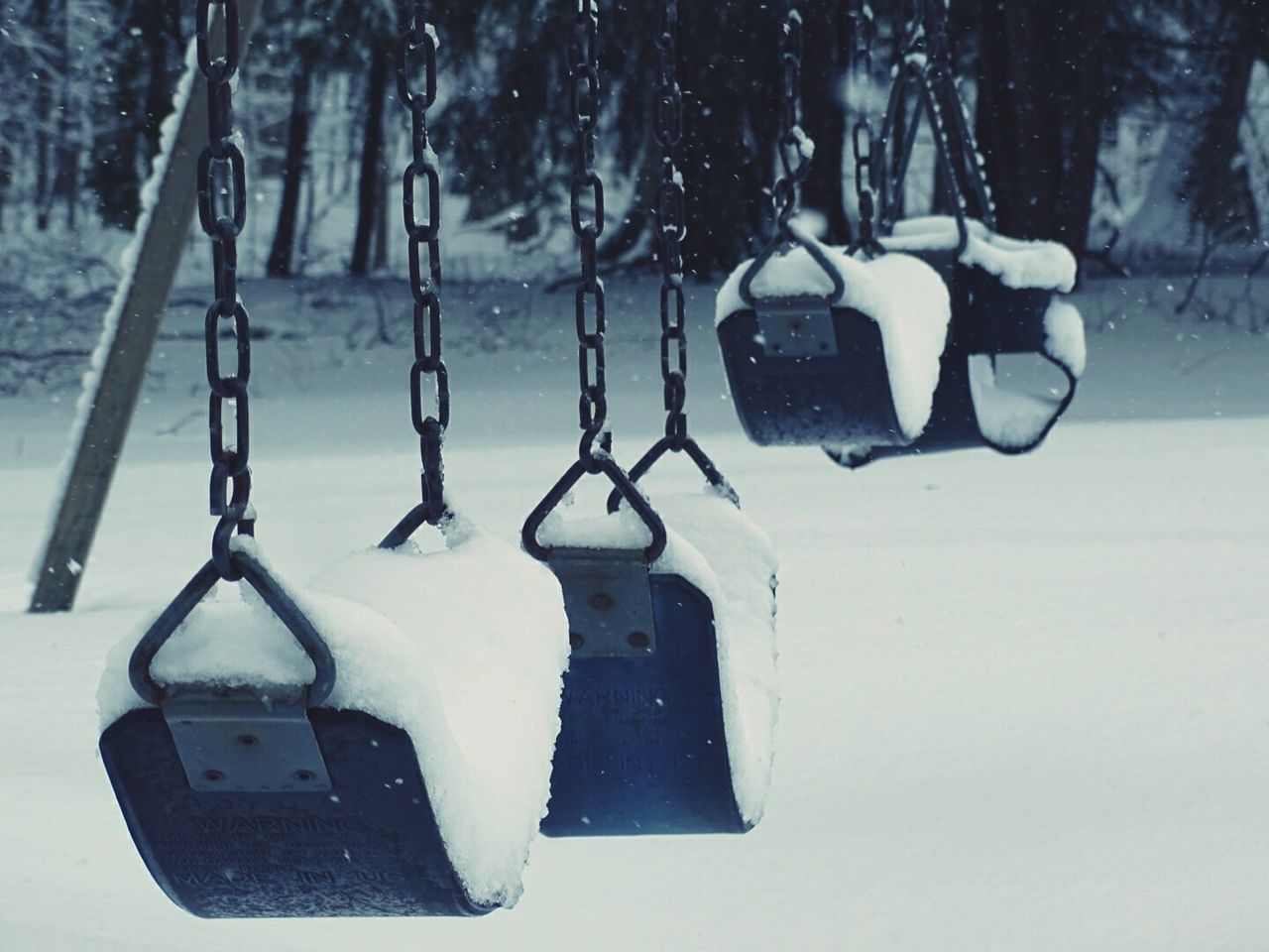 Snow covered swings hanging at park