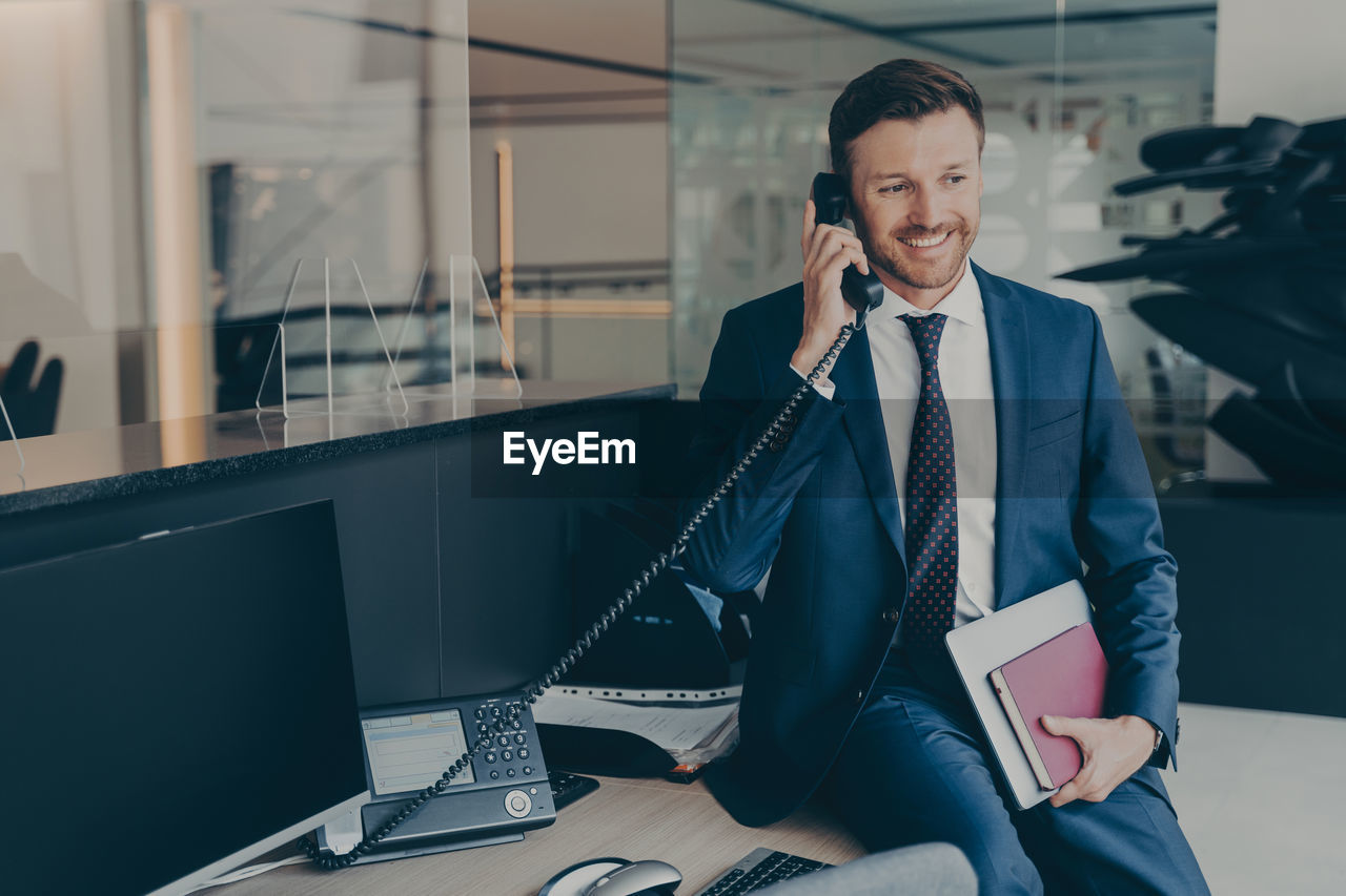 young businesswoman using mobile phone while sitting in office