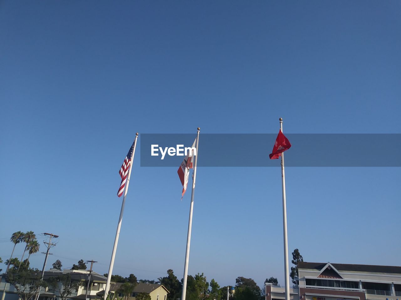 LOW ANGLE VIEW OF FLAGS AGAINST BLUE SKY