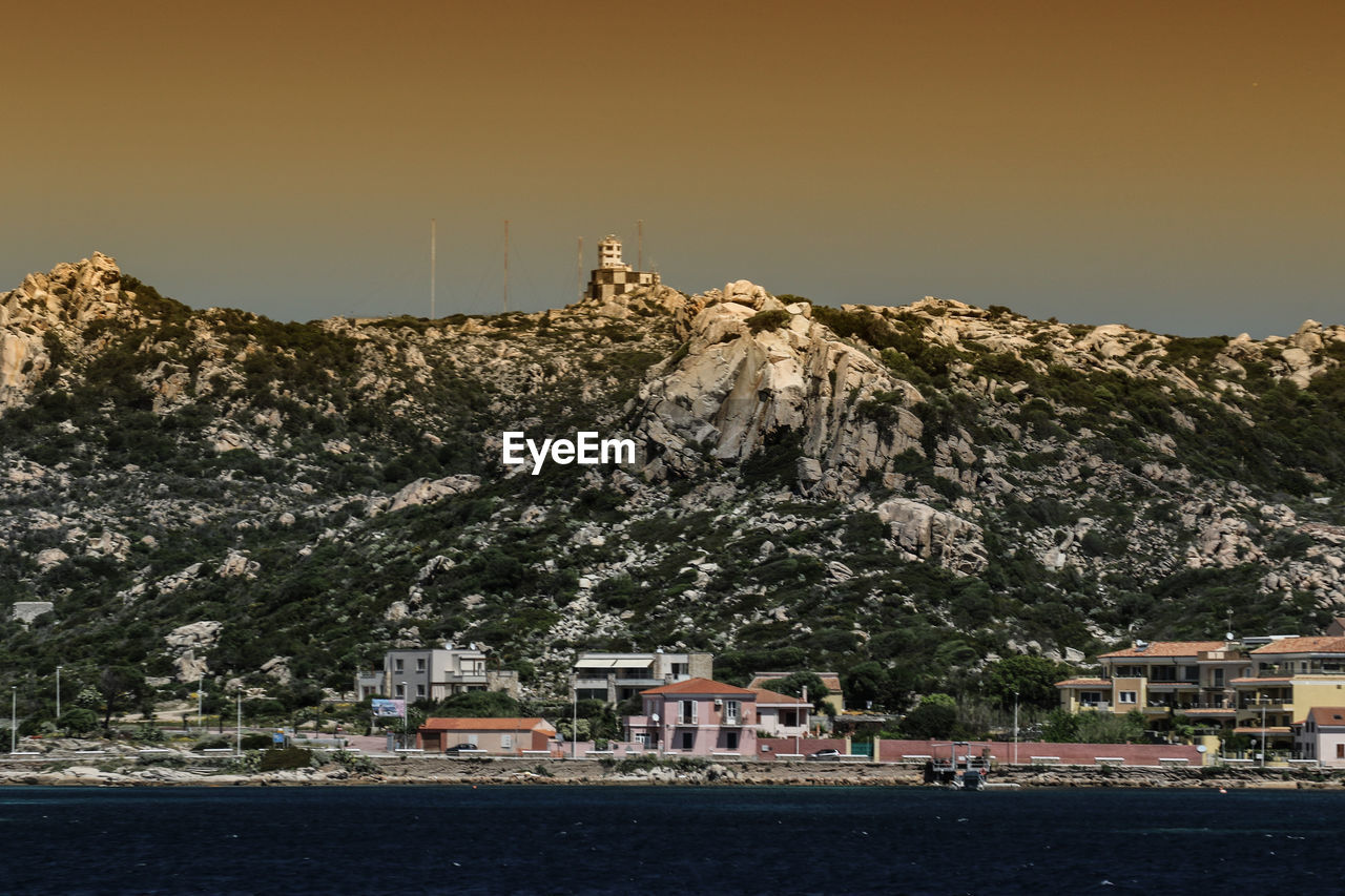 BUILDINGS BY MOUNTAIN AGAINST SKY