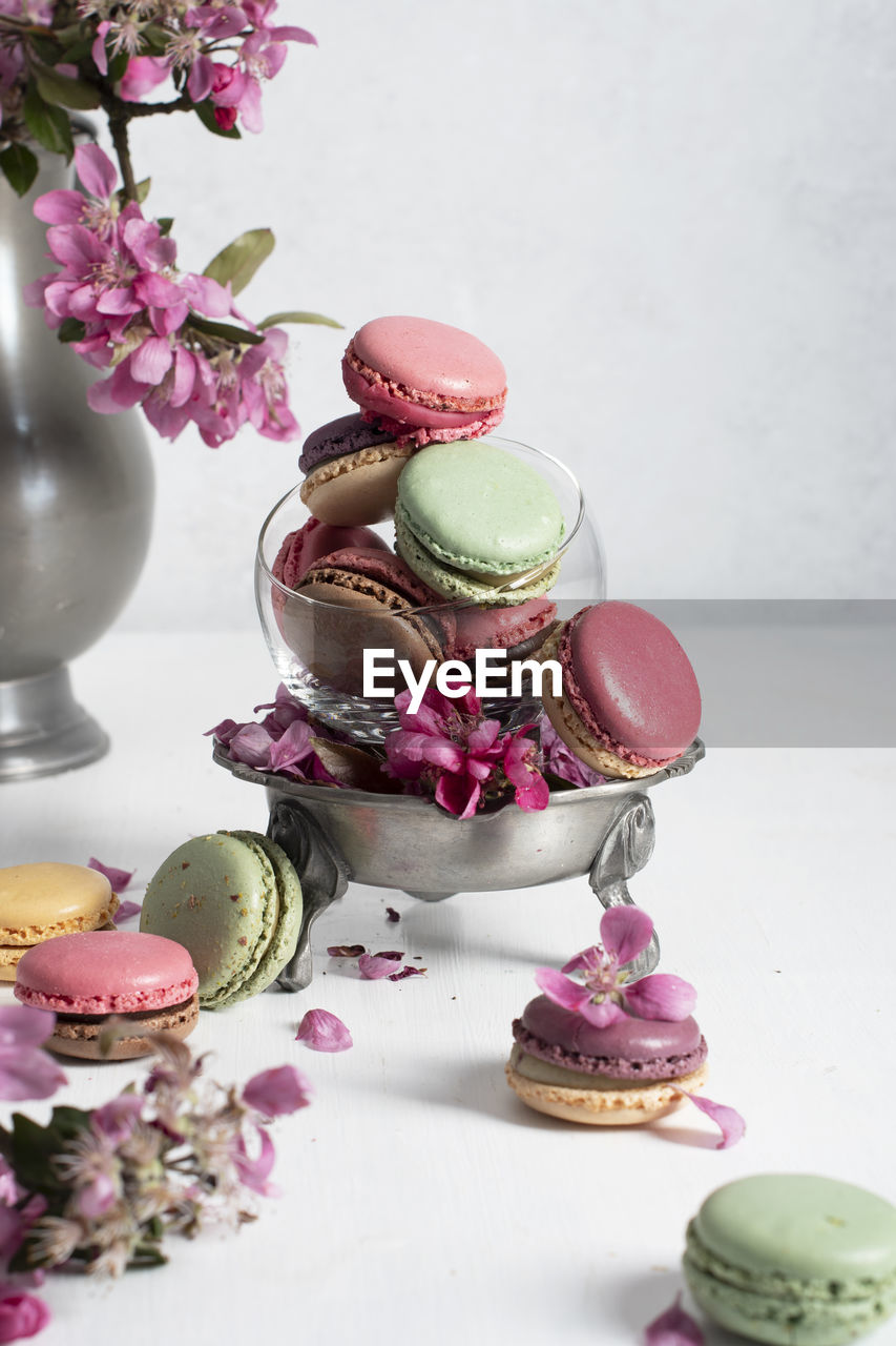 Spring still life with colored macaroons and pink apple tree flowers in a pewter