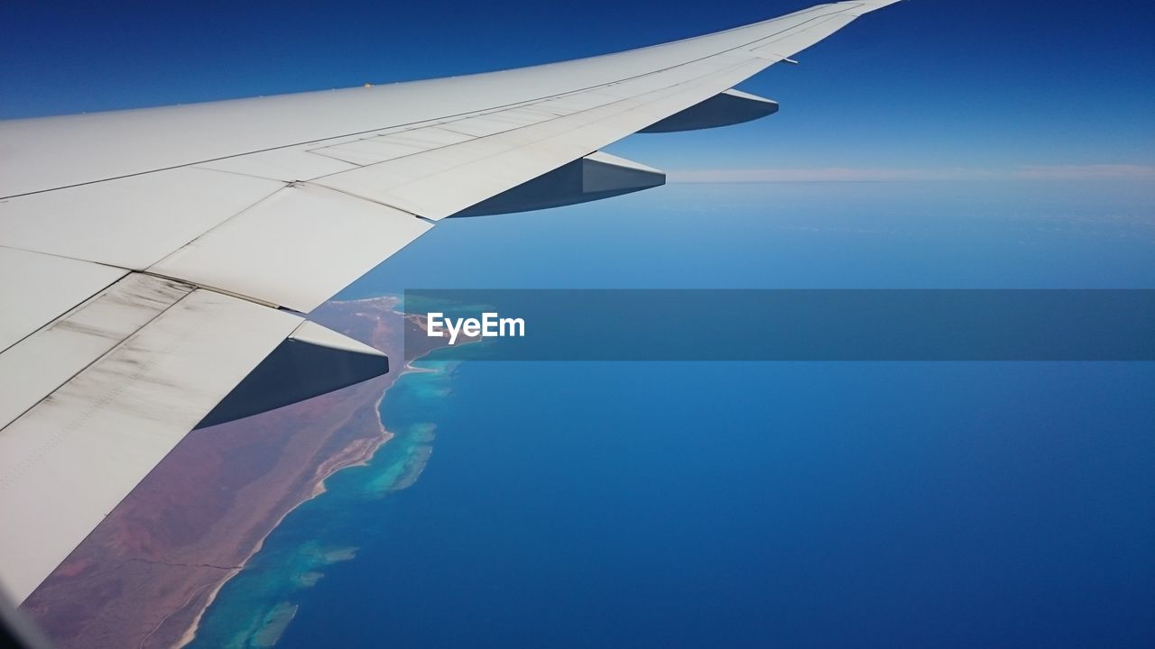 CLOSE-UP OF AIRPLANE WING OVER SEA AGAINST SKY