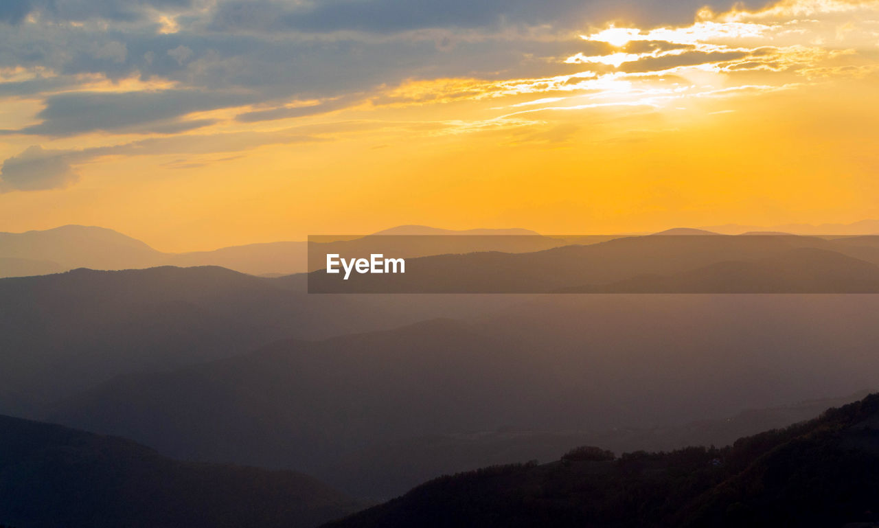 Scenic view of silhouette mountains against orange sky