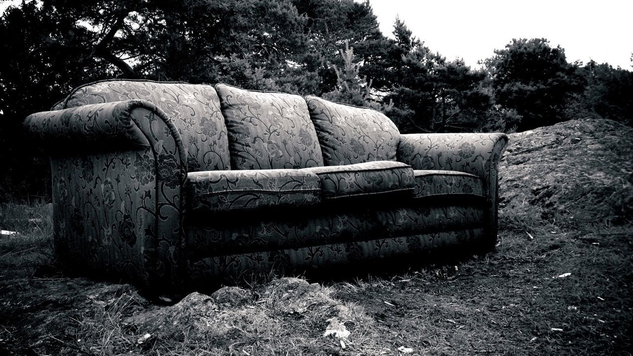 Abandoned sofa on grassy field