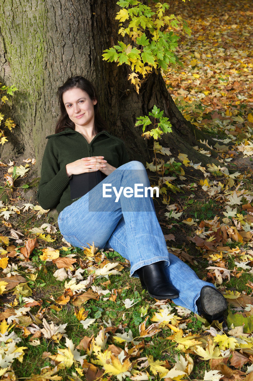 Portrait of young woman relaxing on field during autumn at herrenhausen gardens