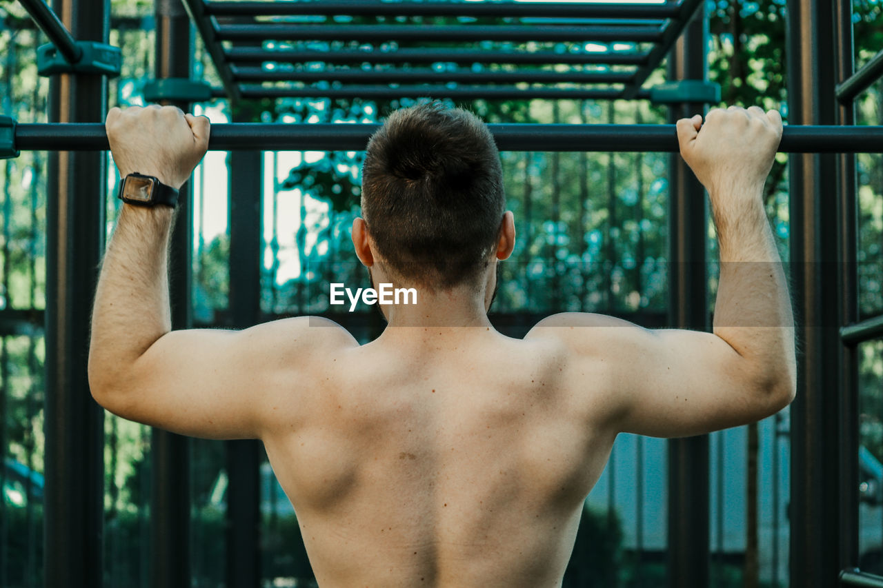 Rear view of shirtless man looking at camera