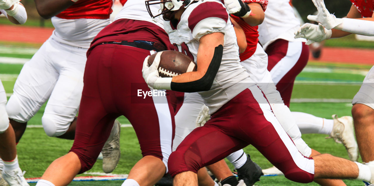 American football player running with the ball behind his blockers during a game