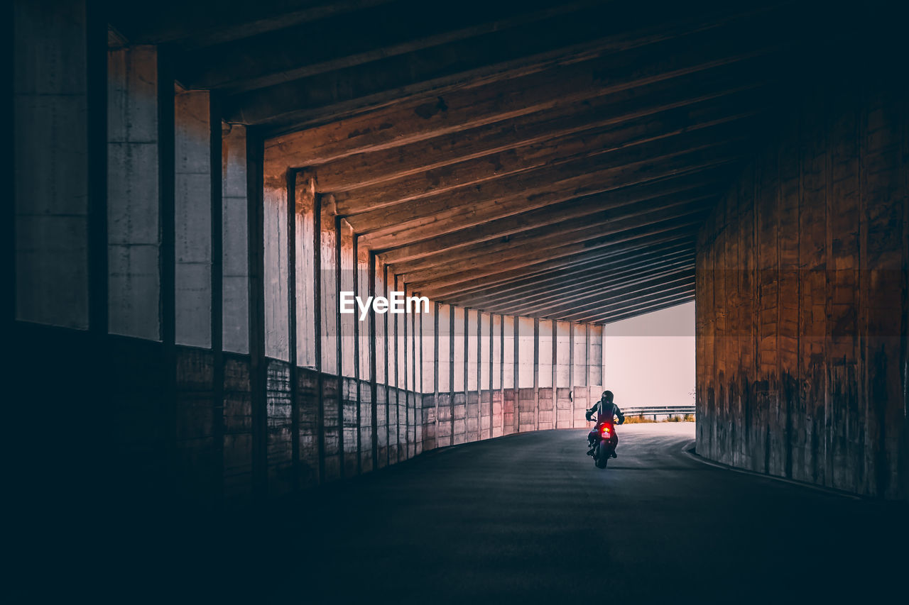 Rear view of man biking in tunnel