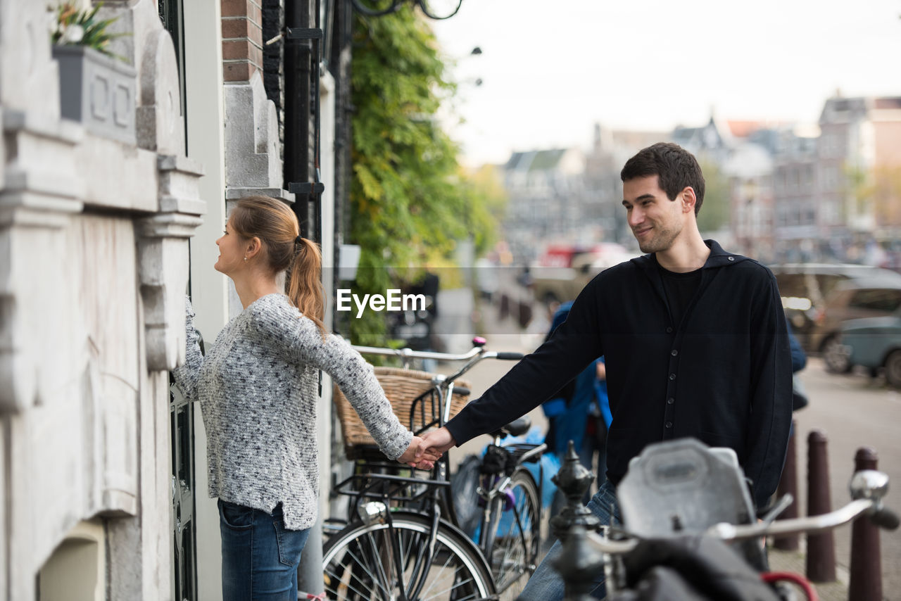 Young couple holding hands by building in city