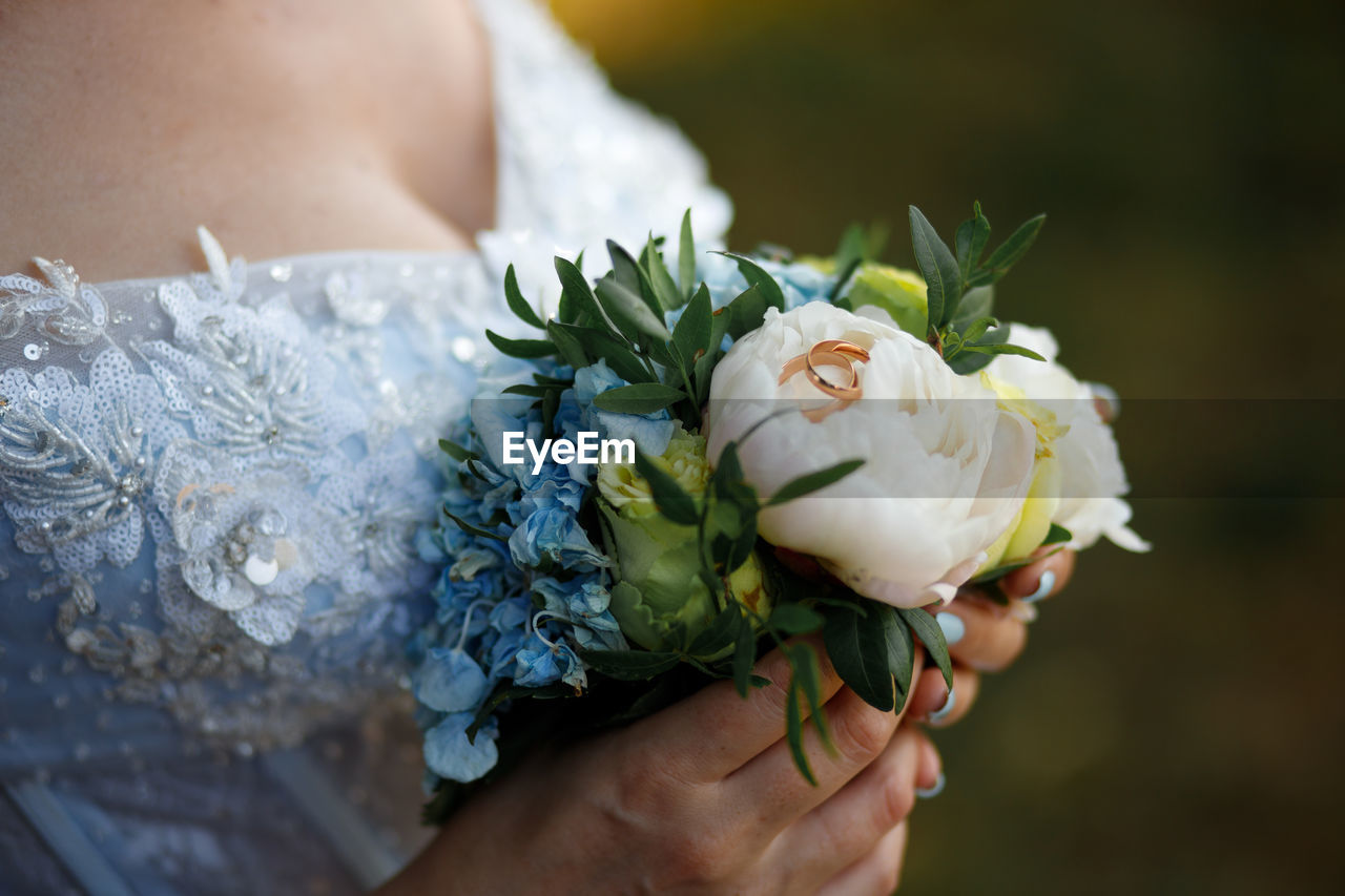 Midsection of bride holding bouquet