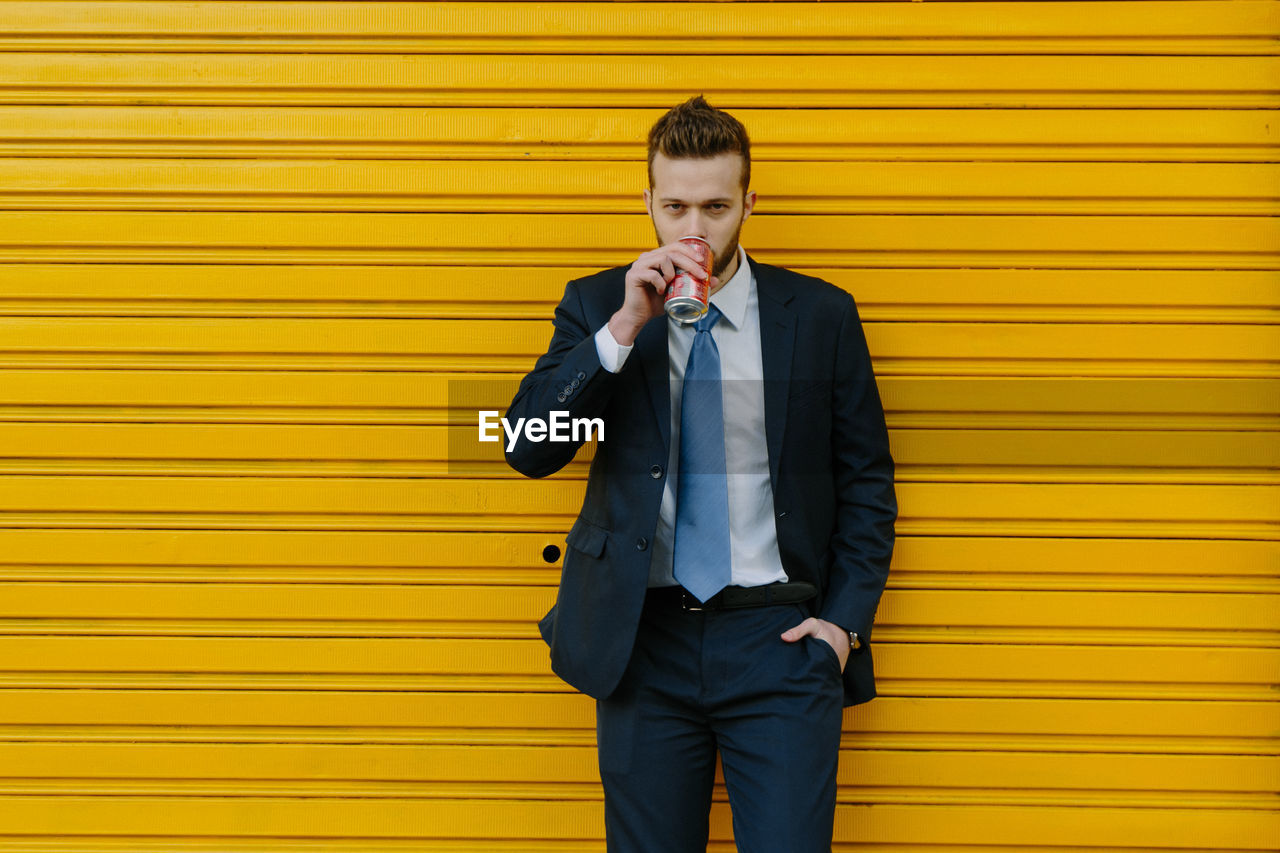 FULL LENGTH OF A MAN STANDING AGAINST YELLOW WALL