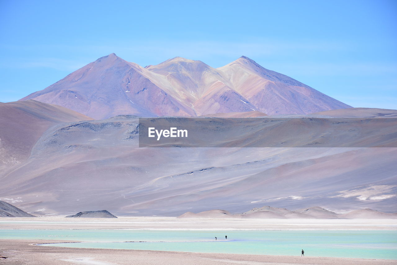Scenic view of sea by mountains against sky